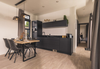 Cocina negra moderna y comedor en Villa Maritiem de MarinaPark Bad Nederrijn, Países Bajos, con decoración elegante.