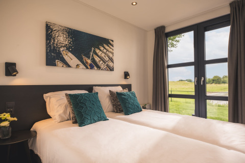 Lyst og moderne soveværelse i Villa Maritiem på MarinaPark Bad Nederrijn med store vinduer og naturskøn udsigt.