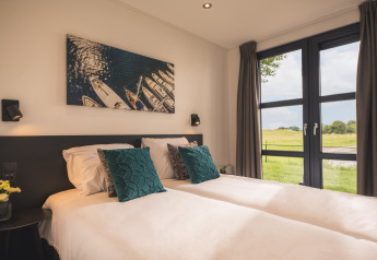 Lyst og moderne soveværelse i Villa Maritiem på MarinaPark Bad Nederrijn med store vinduer og naturskøn udsigt.