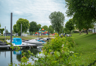 Vista de Villa Maritiem en MarinaPark Bad Nederrijn, Países Bajos, con muelle, zona verde y parque infantil.