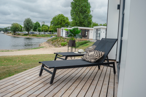 Terrazza solarium con lettini e cuscini presso Villa Maritiem, vista lago a MarinaPark Bad Nederrijn, Paesi Bassi.