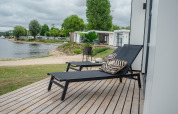 Solterrasse med liggestole og puder ved Villa Maritiem, med udsigt over søen i MarinaPark Bad Nederrijn, Nederlandene.