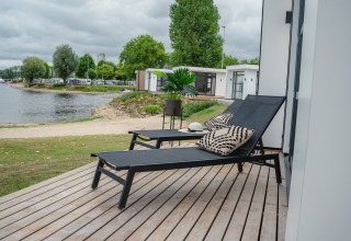 Zonneterras met ligstoelen en kussens bij Villa Maritiem met zicht op het meer in MarinaPark Bad Nederrijn.