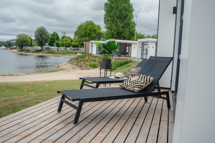 Terraza con tumbonas y cojines en Villa Maritiem, con vistas al lago en MarinaPark Bad Nederrijn, Países Bajos.