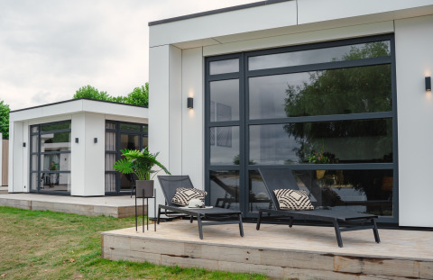 Villa moderna con grandes ventanales y tumbonas en la terraza en MarinaPark Bad Nederrijn, Países Bajos.