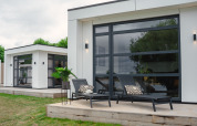 Moderne villa met grote ramen en ligstoelen op het terras bij MarinaPark Bad Nederrijn in Nederland.