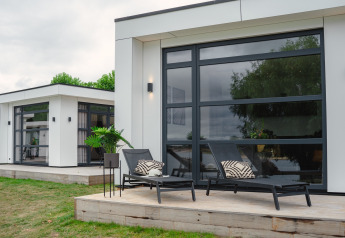 Moderne villa met grote ramen en ligstoelen op het terras bij MarinaPark Bad Nederrijn in Nederland.