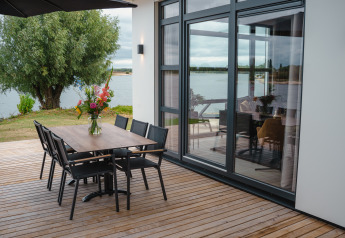 Terras van Villa Maritiem bij MarinaPark Bad Nederrijn, Nederland, met eettafel, stoelen en uitzicht op het water.