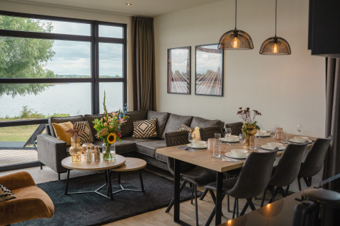 Soggiorno e sala da pranzo moderni con vista lago a Villa Maritiem, MarinaPark Bad Nederrijn, Paesi Bassi.