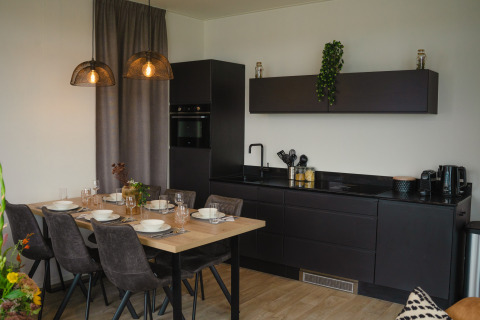 Cucina e zona pranzo moderne a Villa Maritiem, MarinaPark Bad Nederrijn, Paesi Bassi, con arredi neri eleganti.