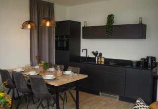 Cucina e zona pranzo moderne a Villa Maritiem, MarinaPark Bad Nederrijn, Paesi Bassi, con arredi neri eleganti.