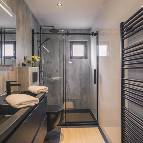 Bagno moderno con doccia in vetro, accessori neri e asciugamani nella Villa Maritiem a MarinaPark Bad Nederrijn, Paesi Bassi.