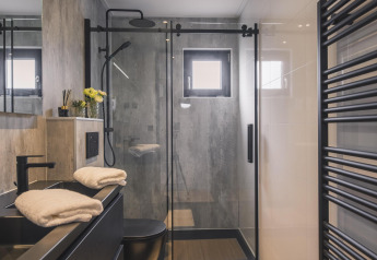 Baño moderno con ducha de cristal, grifería negra y toallas en Villa Maritiem en MarinaPark Bad Nederrijn, Países Bajos.