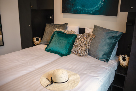 Gezellige slaapkamer in Villa Maritiem, MarinaPark Bad Nederrijn, Nederland, met sierkussens en hoed.