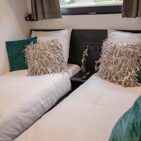 Twee eenpersoonsbedden met sierkussens in Villa Maritiem, MarinaPark Bad Nederrijn, Nederland.