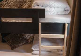 Cama litera con escalera de madera, almohadas y ropa de cama en Villa Maritiem, MarinaPark Bad Nederrijn, Países Bajos.