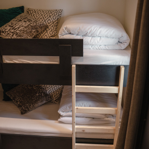 Stapelbed met houten ladder, kussens en beddengoed in een kamer van Villa Maritiem, MarinaPark Bad Nederrijn.