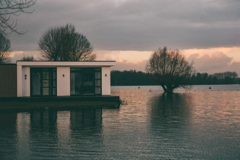 Villa moderna sul lungolago a MarinaPark Bad Nederrijn, Paesi Bassi, tra alberi e acqua al tramonto.