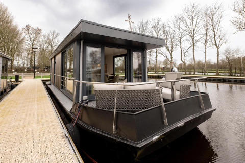 Casa flotante moderna Offingawier en Welcome In - Friesland, Países Bajos, amarrada junto a un muelle.