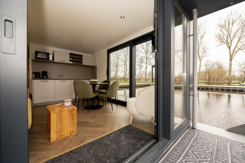 Intérieur d'une péniche moderne à Welcome In - Friesland, Pays-Bas, avec vue sur l'eau et les arbres.