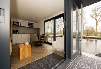 Intérieur d'une péniche moderne à Welcome In - Friesland, Pays-Bas, avec vue sur l'eau et les arbres.