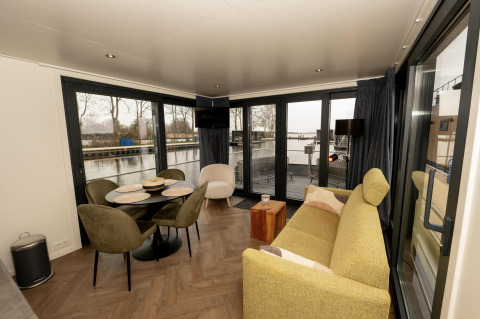Sala de estar de la casa flotante Offingawier en Friesland, Países Bajos, vistas al agua y decoración moderna.