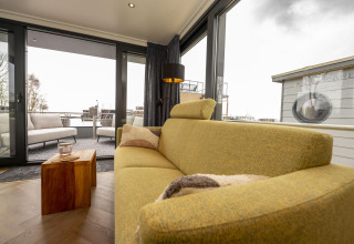 Sala de estar con sofá moderno en Houseboat Offingawier en Welcome In - Friesland, Países Bajos, vista al exterior.