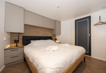 Camera moderna sulla Houseboat Offingawier a Welcome In - Friesland, Paesi Bassi, con letto matrimoniale e arredo elegante.