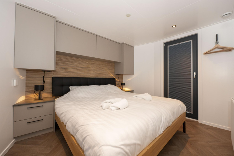 Dormitorio moderno en Houseboat Offingawier en Welcome In - Friesland, Países Bajos, con cama doble y decoración elegante.