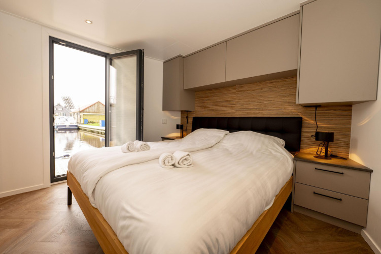 Dormitorio en Houseboat Offingawier en Welcome In - Friesland, Países Bajos, con vistas al canal.