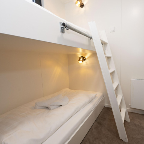 Modernes Etagenbett mit weißer Leiter, frischer Bettwäsche und Beleuchtung auf dem Hausboot Offingawier.