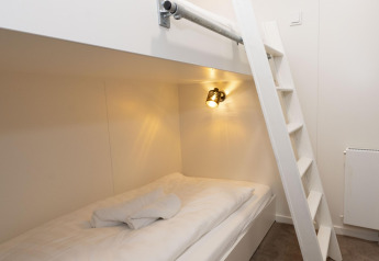 Letto a castello moderno con scala bianca, lenzuola pulite e luci su Houseboat Offingawier in Friesland.