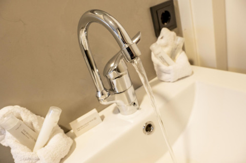 Lavabo avec robinet ouvert et articles de toilette sur Houseboat Offingawier à Welcome In - Friesland, Pays-Bas.