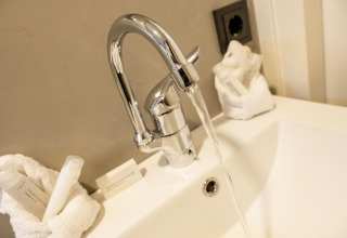 Lavabo avec robinet ouvert et articles de toilette sur Houseboat Offingawier à Welcome In - Friesland, Pays-Bas.