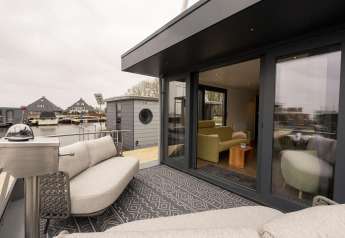 Zona lounge esterna su Houseboat Offingawier con divani moderni e vista sull’acqua in Frisia, Paesi Bassi.