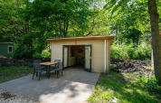 Udendørsbillede af Forest Lodge-hytte ved Het Amsterdamse Bos i Holland med bord og stole på terrassen.