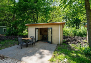 Vista exterior de la cabaña Forest Lodge en Het Amsterdamse Bos, Países Bajos, con mesa y sillas en la terraza.