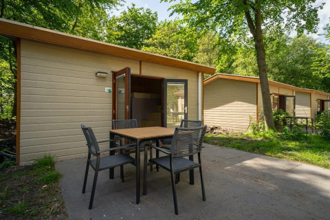 Vista exterior de la cabaña Forest Lodge en Het Amsterdamse Bos, Países Bajos, con mesa y sillas en la terraza.