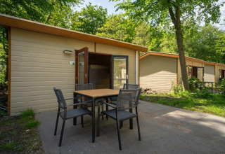 Vista exterior de la cabaña Forest Lodge en Het Amsterdamse Bos, Países Bajos, con mesa y sillas en la terraza.