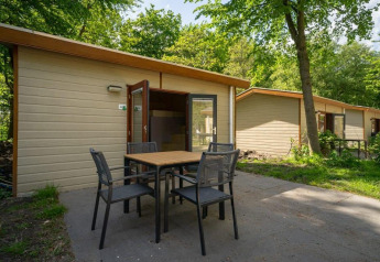 Udendørsbillede af Forest Lodge-hytte ved Het Amsterdamse Bos i Holland med borde og stole på terrassen.