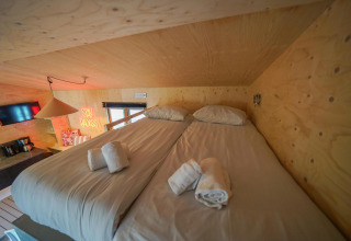 Foto interior del dormitorio en Forest Lodge, Het Amsterdamse Bos, con dos camas bajo un techo de madera.