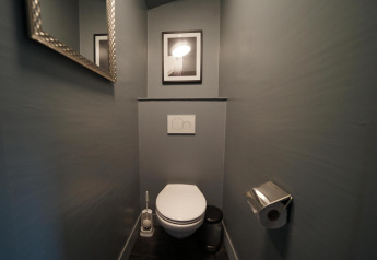 Moderne toilet med vægmonteret cisterne og kunst på væggen i Forest Lodge, Het Amsterdamse Bos, Holland.
