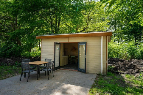 Acogedora cabaña Forest Lodge con terraza y asientos al aire libre en Het Amsterdamse Bos, Países Bajos.