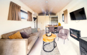 Salon lumineux et chaleureux dans un Tiny House à De Wije Werelt, Pays-Bas, avec canapé et télévision.
