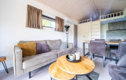 Sala moderna en el Tiny House de De Wije Werelt, Países Bajos, con sofá, comedor y entrepiso visible.