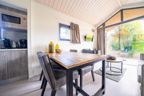 Moderne eet- en zithoek in een Tiny House bij De Wije Werelt, Nederland, met uitzicht op de tuin.
