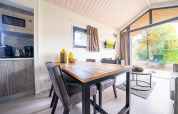 Moderne eet- en zithoek in een Tiny House bij De Wije Werelt, Nederland, met uitzicht op de tuin.