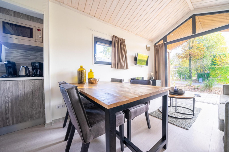 Modern dining and living area in a Tiny House at De Wije Werelt, Netherlands, with a view of the outdoors.