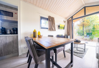 Modern dining and living area in a Tiny House at De Wije Werelt, Netherlands, with a view of the outdoors.