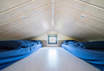 Loftværelse i Tiny House på De Wije Werelt, Holland, med to madrasser og blå sengetøj under skråt tag.